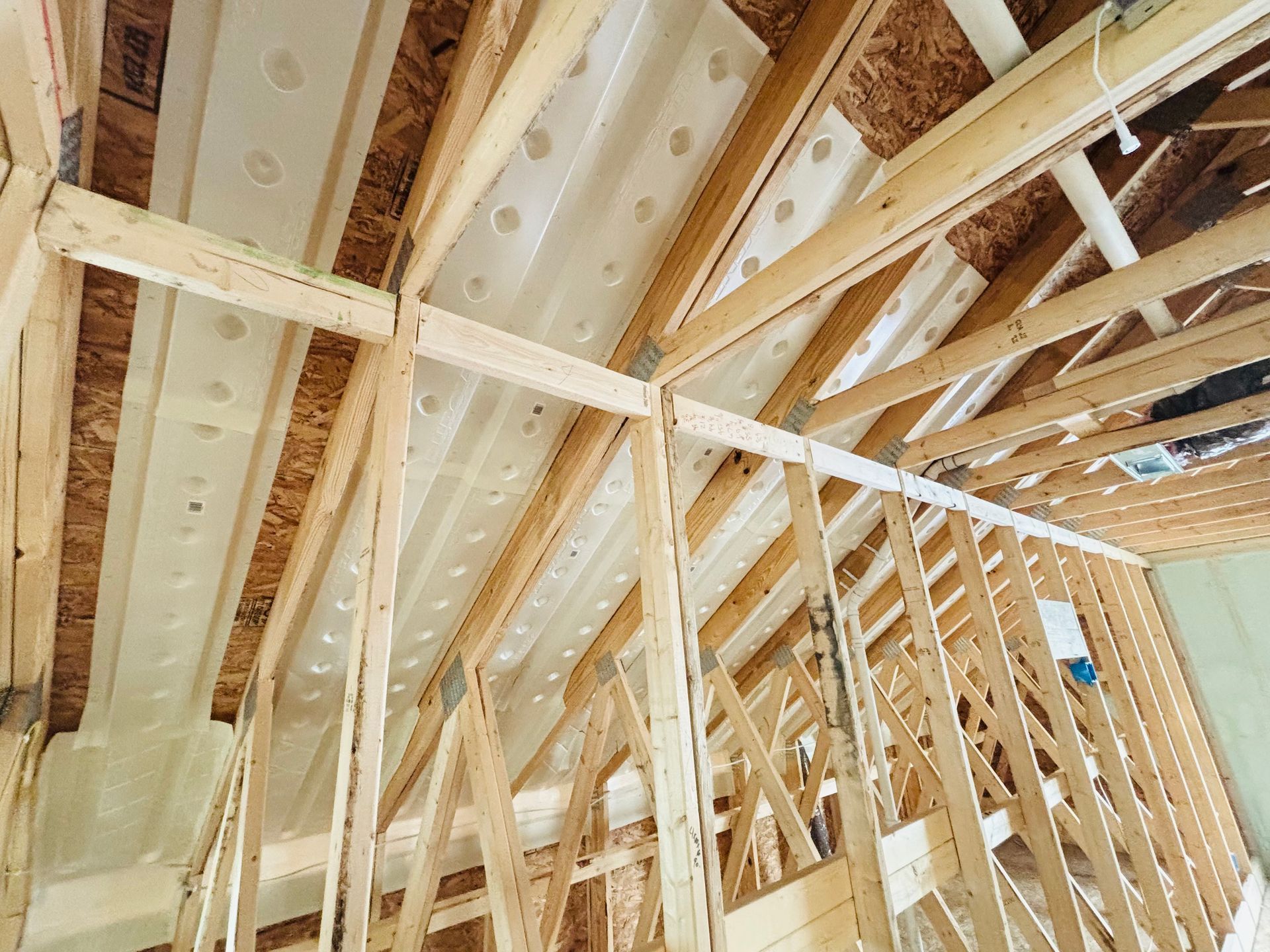 Interior view of a building under construction, showing wooden framing and ceiling insulation.