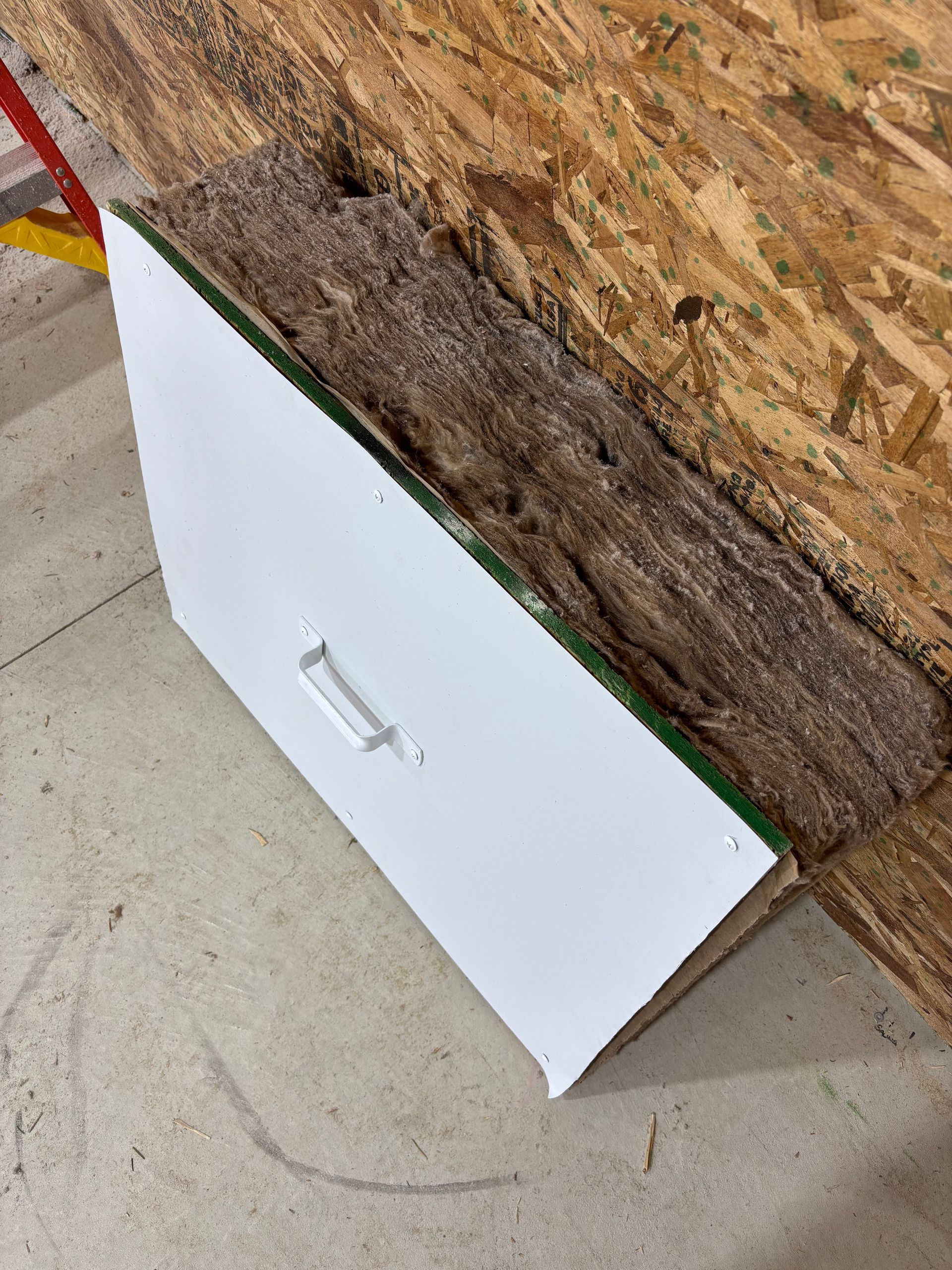 White drawer with handle on the floor next to damaged wood and particleboard.