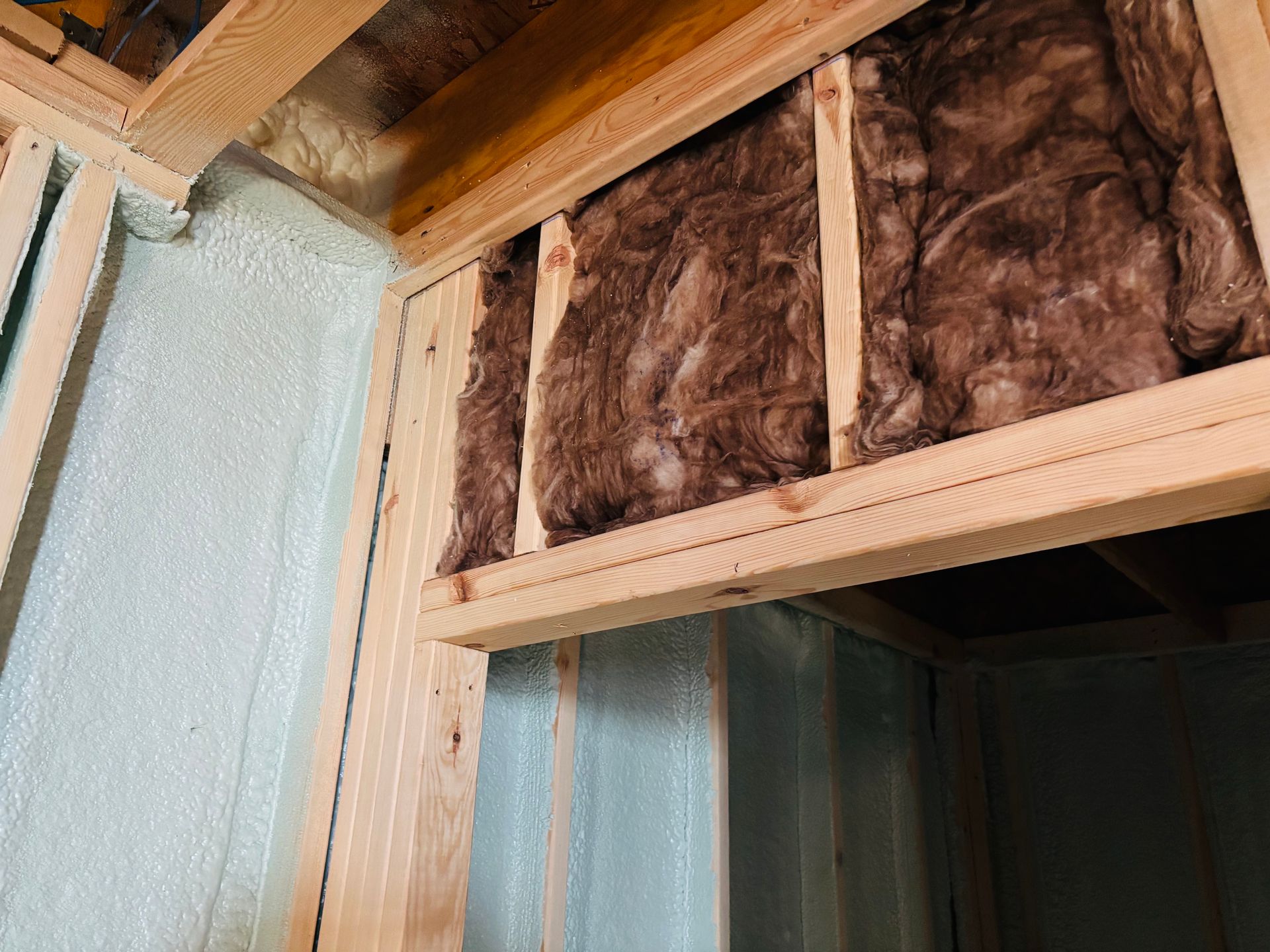 Wooden frame construction with insulation and foam sealant.