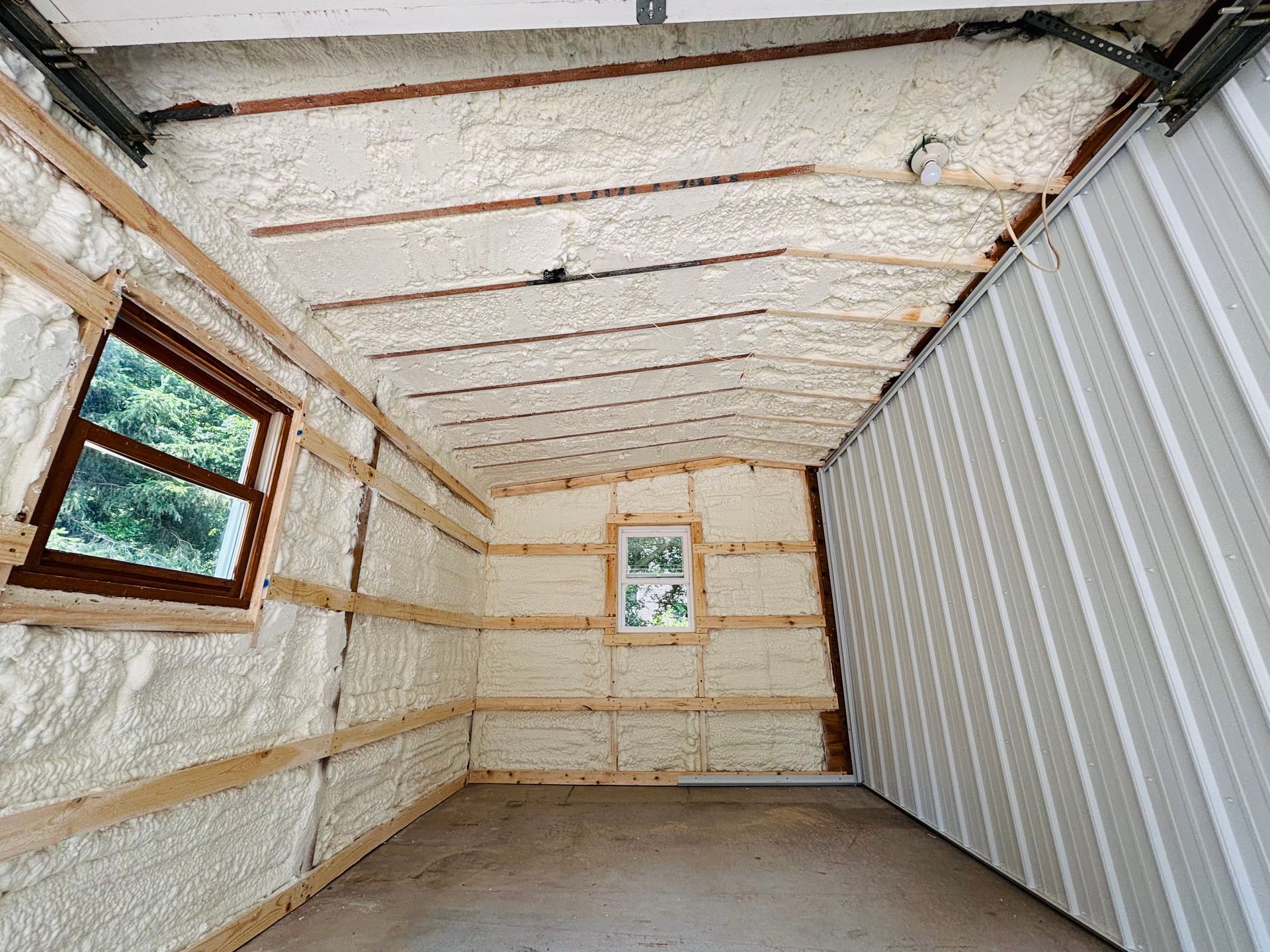 Interior of a building insulated with spray foam. Walls have wooden frames and a window.