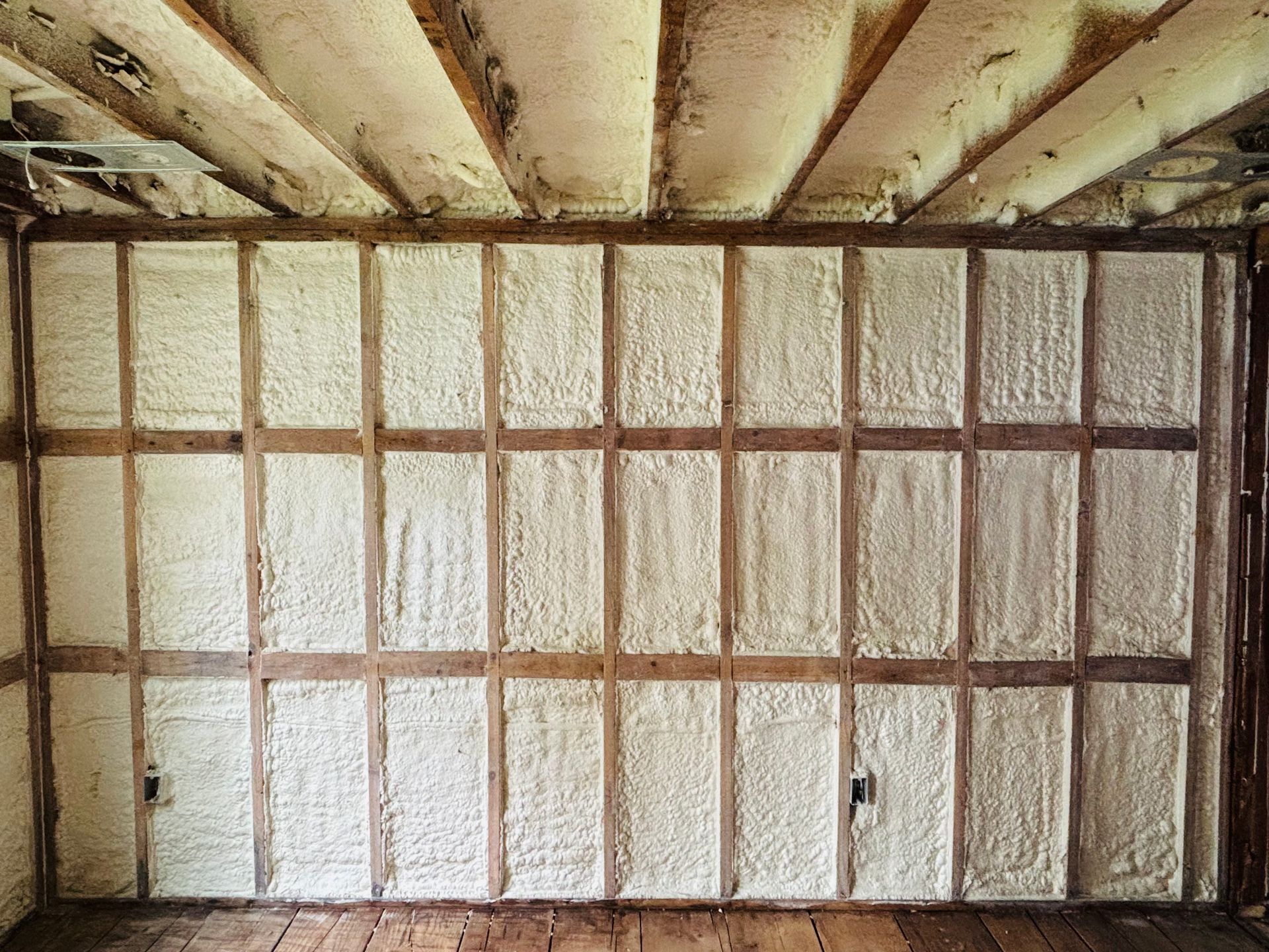 Interior wall with exposed wooden beams and insulation.