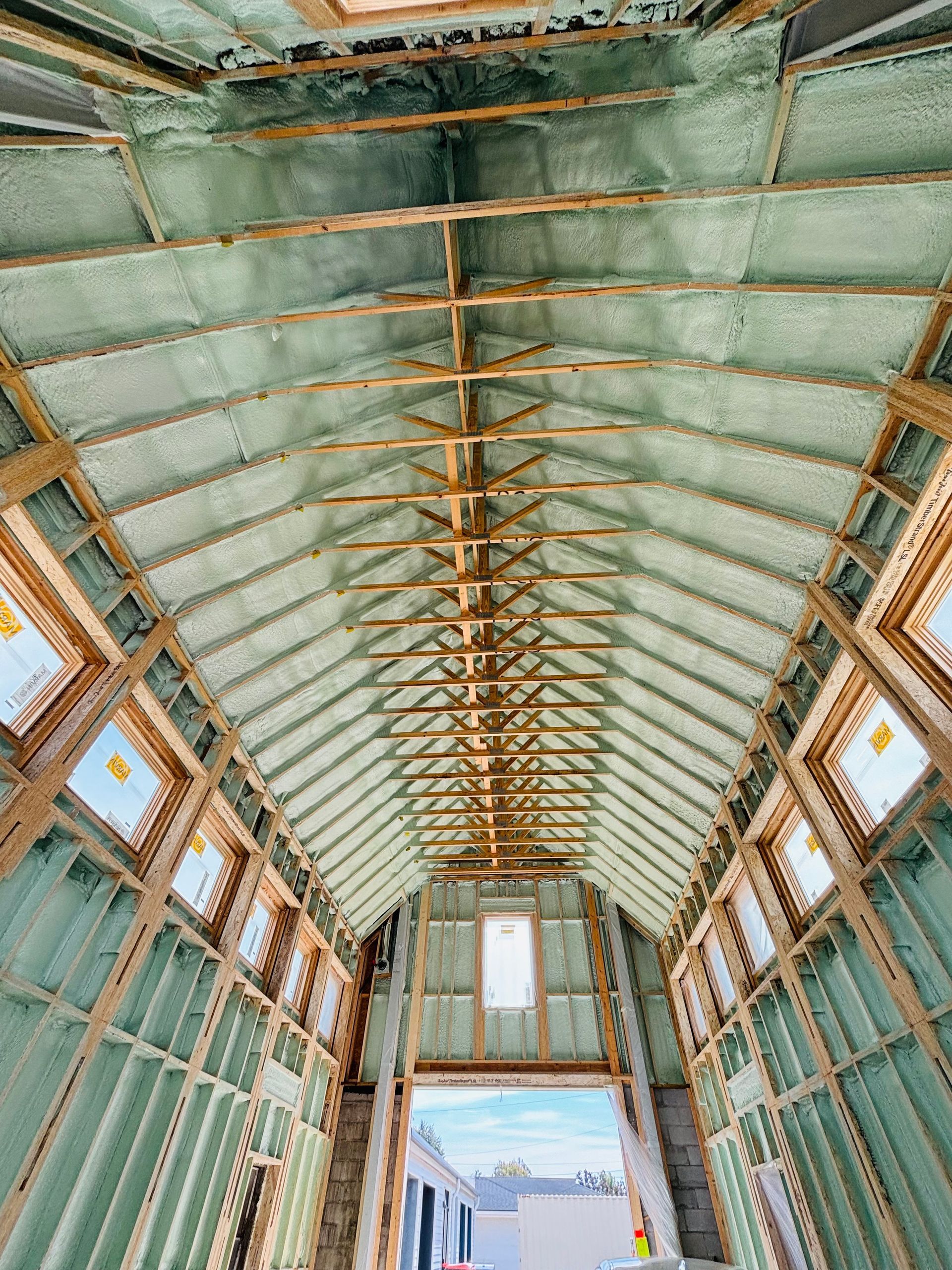 Interior view of a building under construction, featuring wooden beams and green insulation on walls and ceiling.