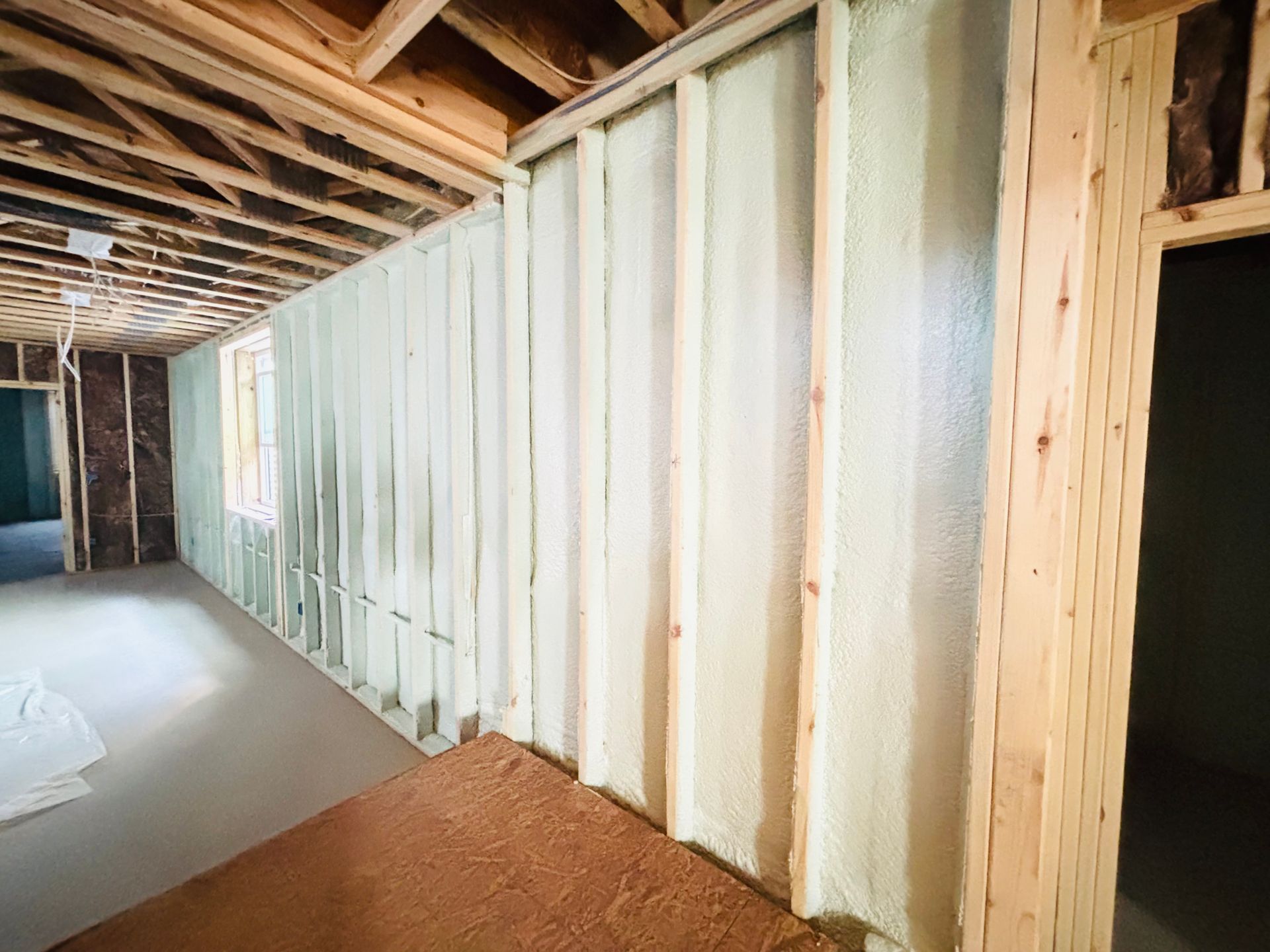 Interior wall construction with spray foam insulation. Wooden studs are visible.