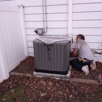 A man is working on an air conditioner outside of a house