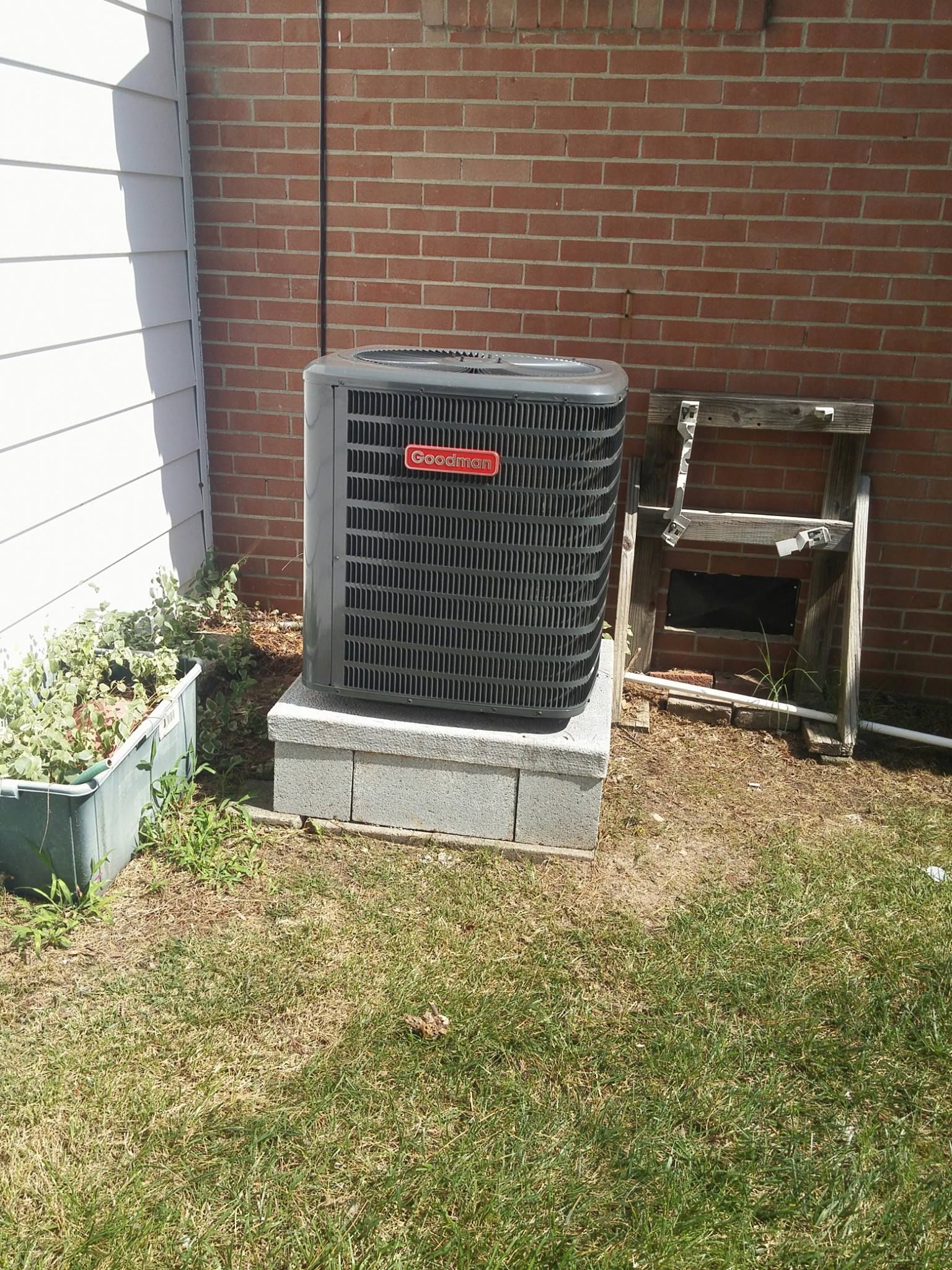 A black air conditioner is sitting on top of a concrete block