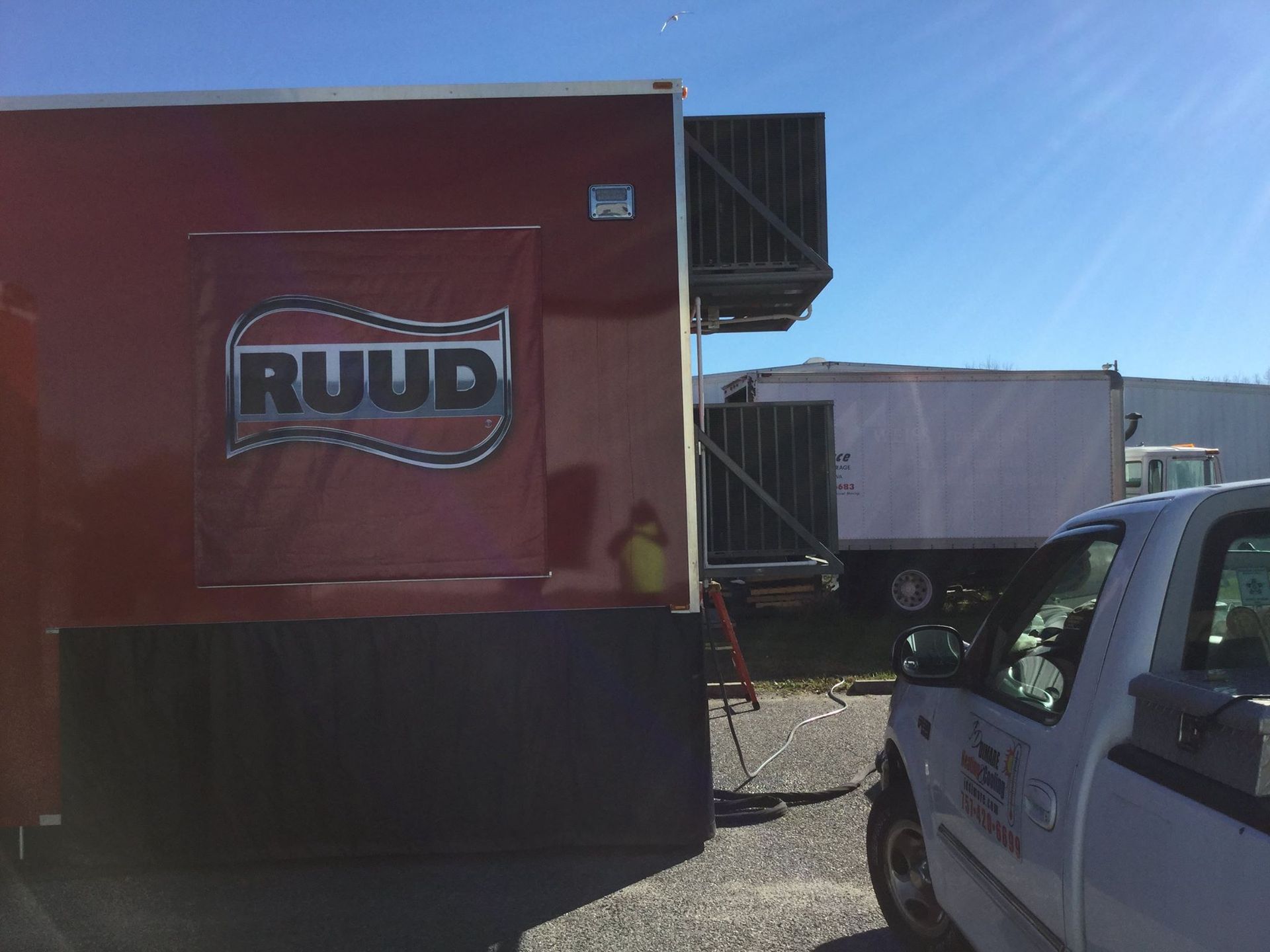 A truck is parked next to a trailer with AC units