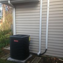 A black air conditioner is sitting on the side of a house