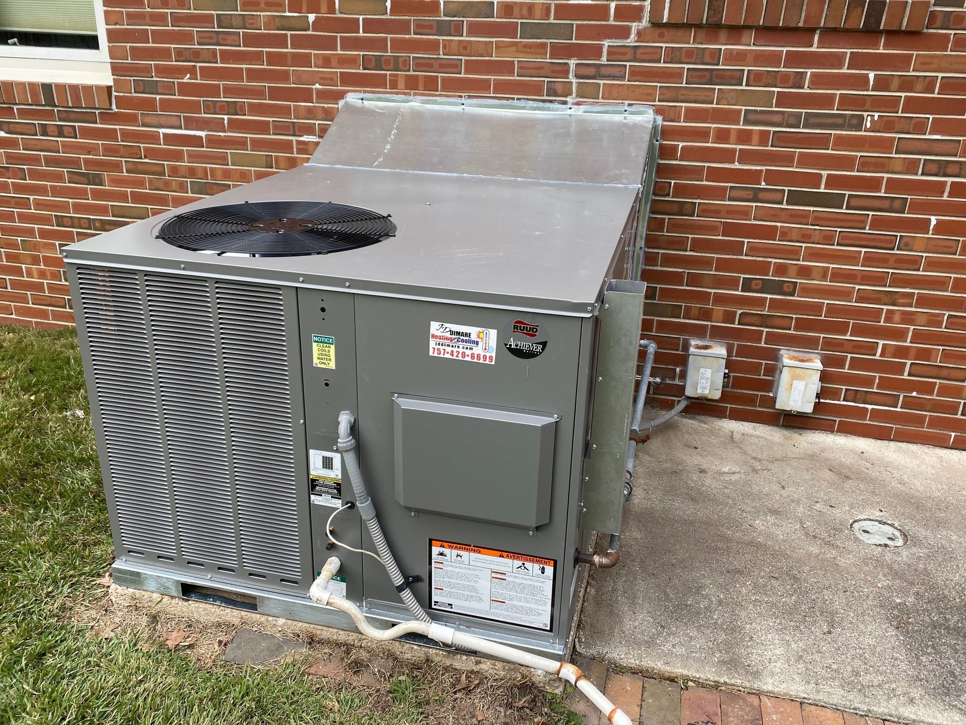 A large air conditioner is sitting on the side of a brick building