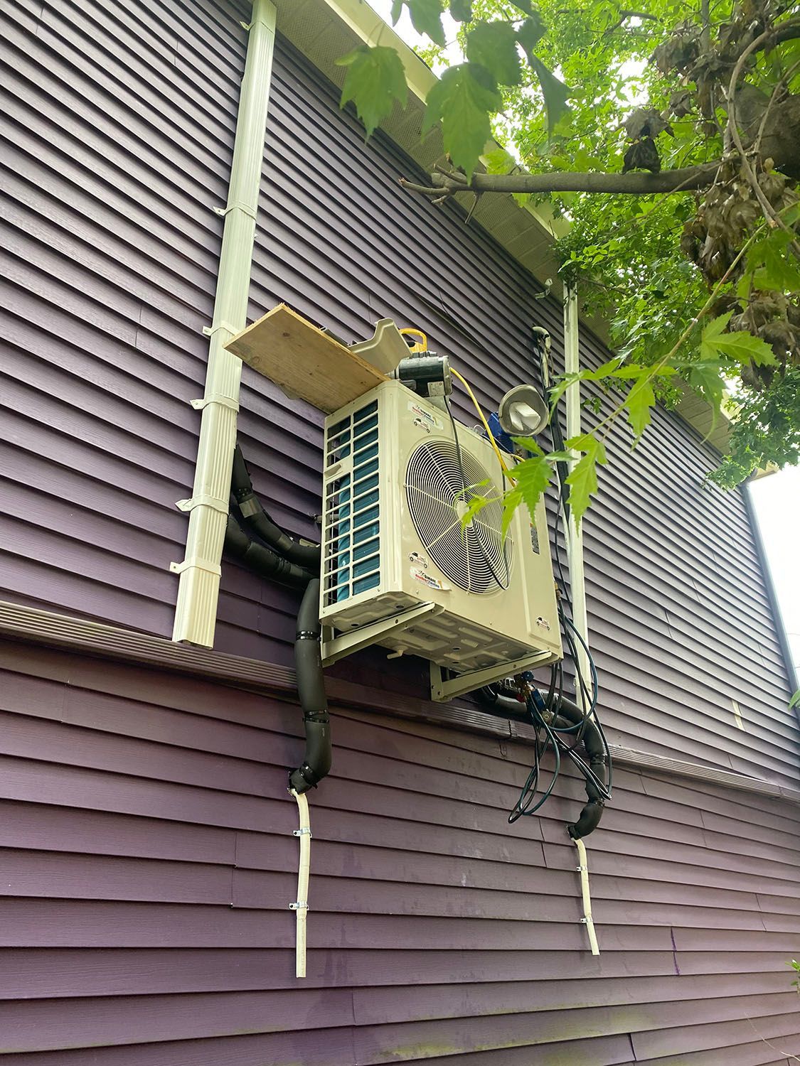 An air conditioner is installed on the side of a purple house