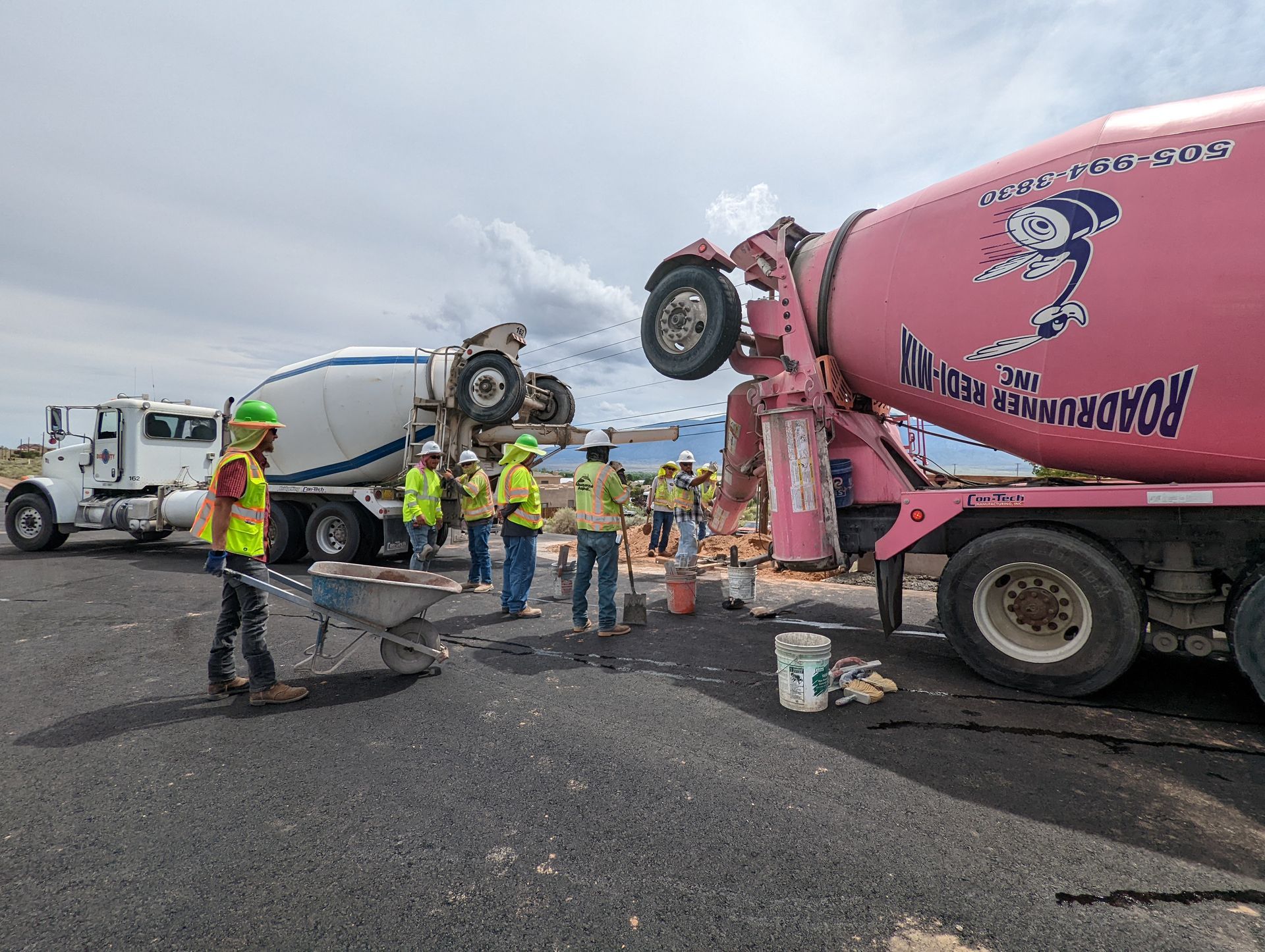 A group of construction workers are standing in front of a pink concrete mixer truck.