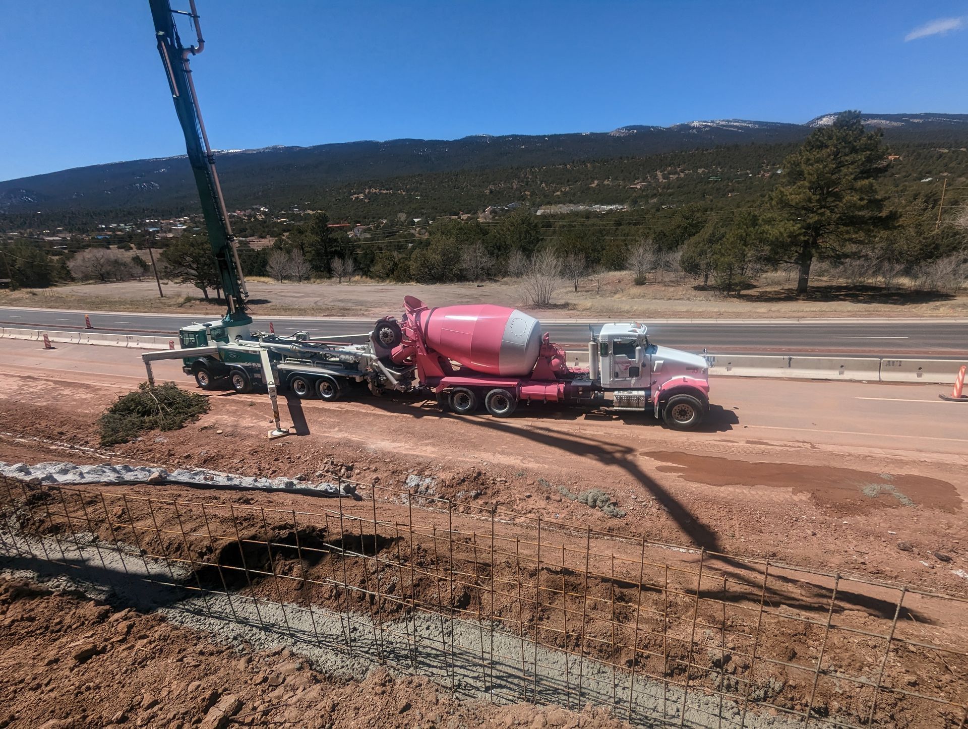 A concrete mixer truck is driving down a dirt road.