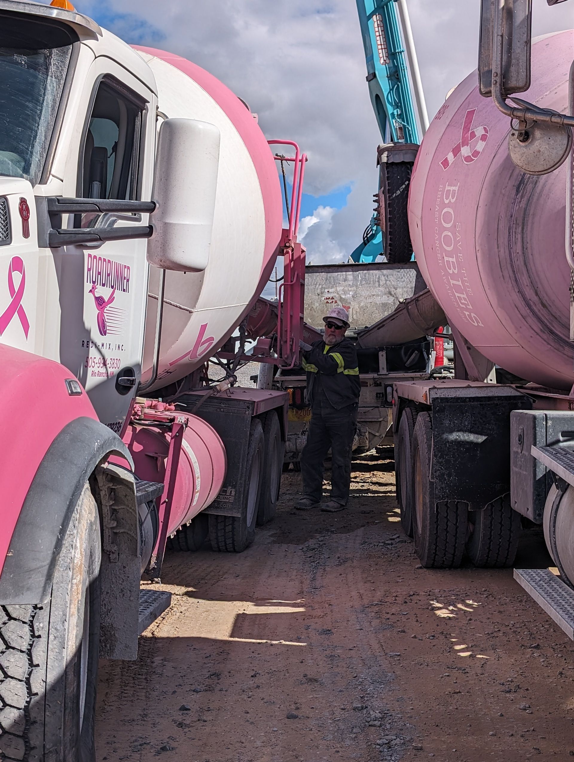A man is standing next to a row of pink and white trucks.