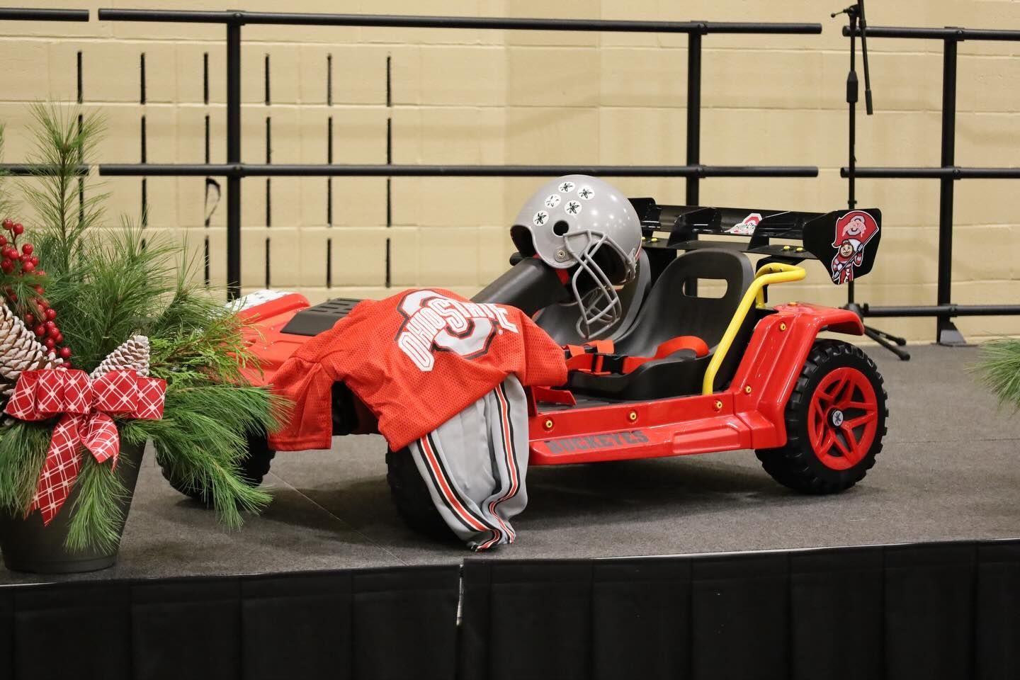 Red toy car decorated with football gear and holiday greenery.
