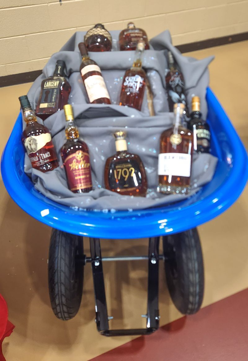 A blue wheelbarrow filled with bottles of whiskey