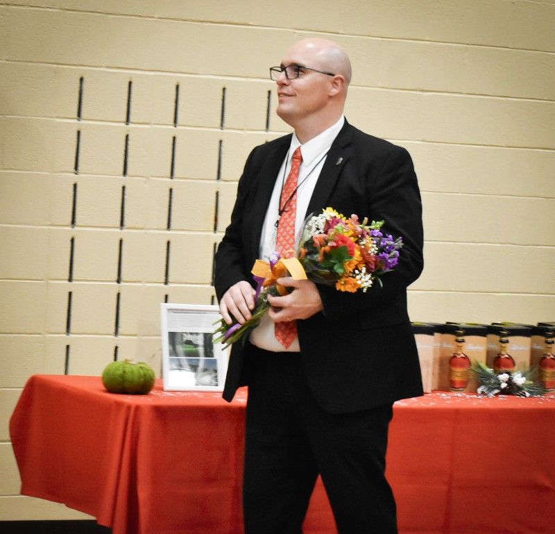 A man in a suit and tie is holding a bouquet of flowers