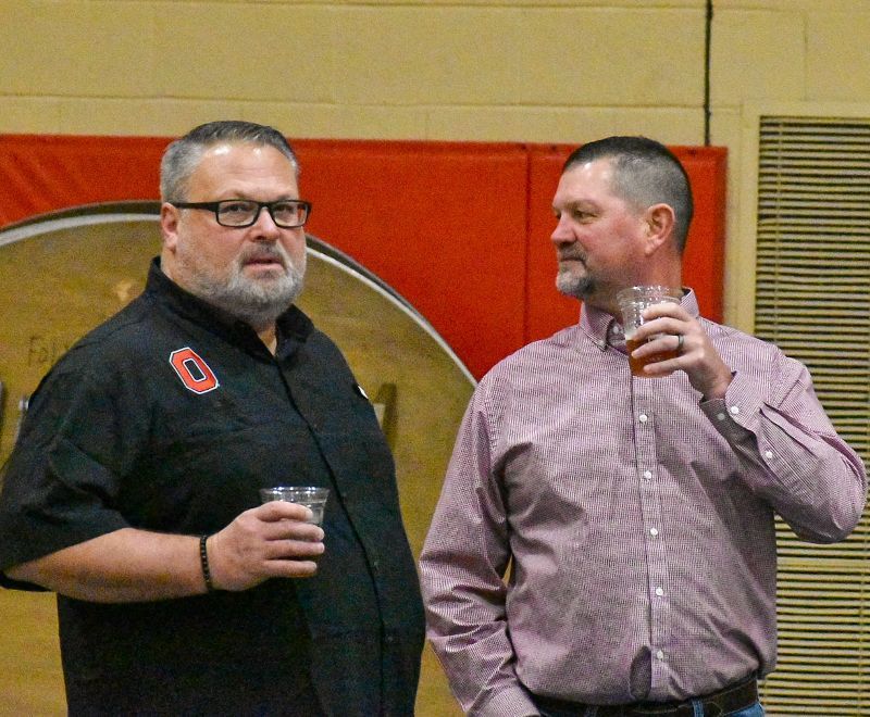 Two men are standing next to each other and one has the letter o on his shirt