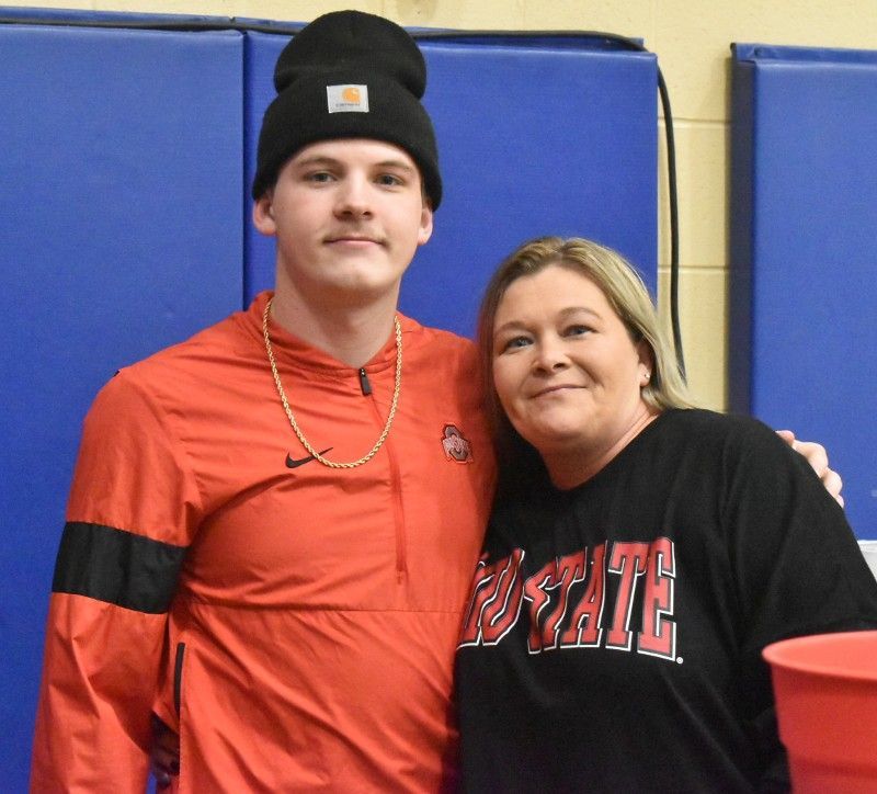 A man and a woman are posing for a picture and the woman is wearing a shirt that says state