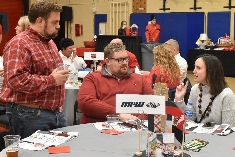 A group of people are sitting around a table with a sign that says mpl on it.