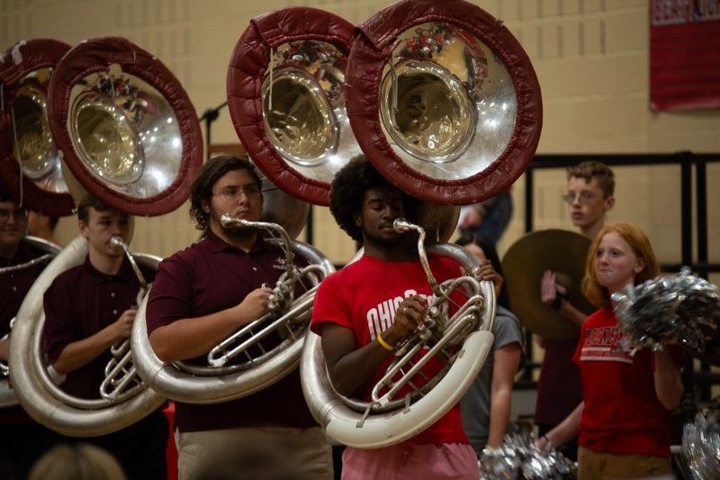 A man in a red shirt is playing a trombone in a band.