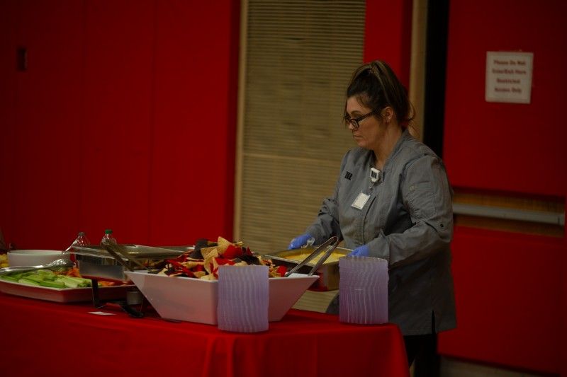 A woman is serving food at a buffet table.