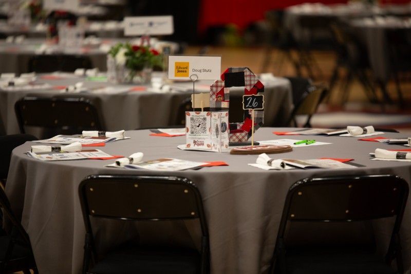 A round table with a gray table cloth and black chairs in a room.