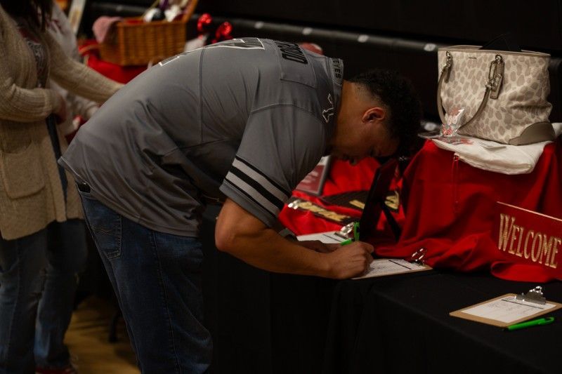 A man is writing on a piece of paper at a table.