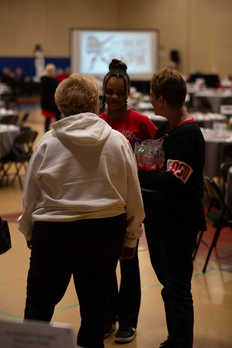 A group of women are standing in a room talking to each other.
