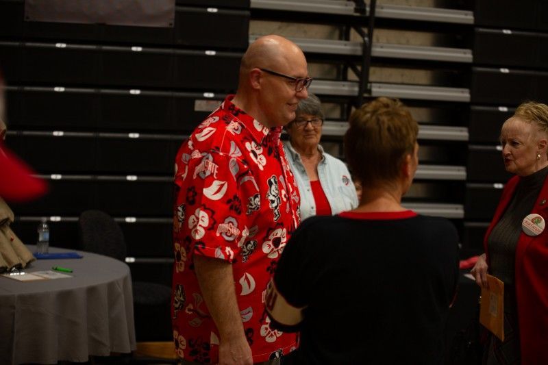 A man in a red shirt is standing next to a woman in a black shirt.
