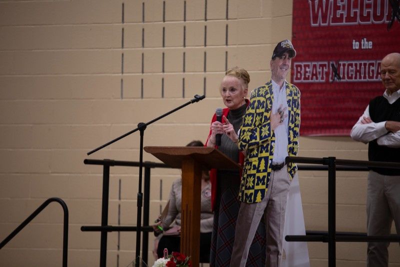 A woman stands at a podium in front of a sign that says welcome