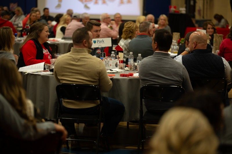 A group of people are sitting at tables in a room watching a presentation.