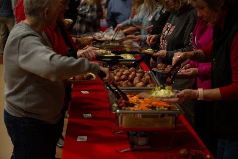 A group of people are standing around a table eating food.