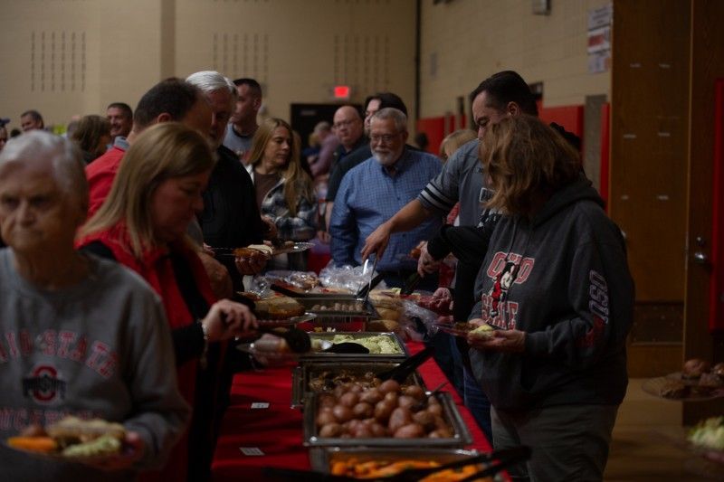 A group of people are standing around a table eating food.