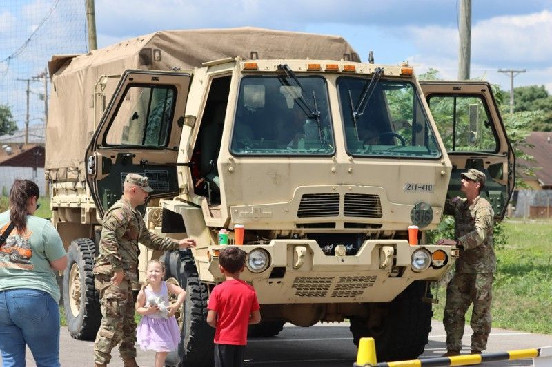 A group of people are standing around a military truck.
