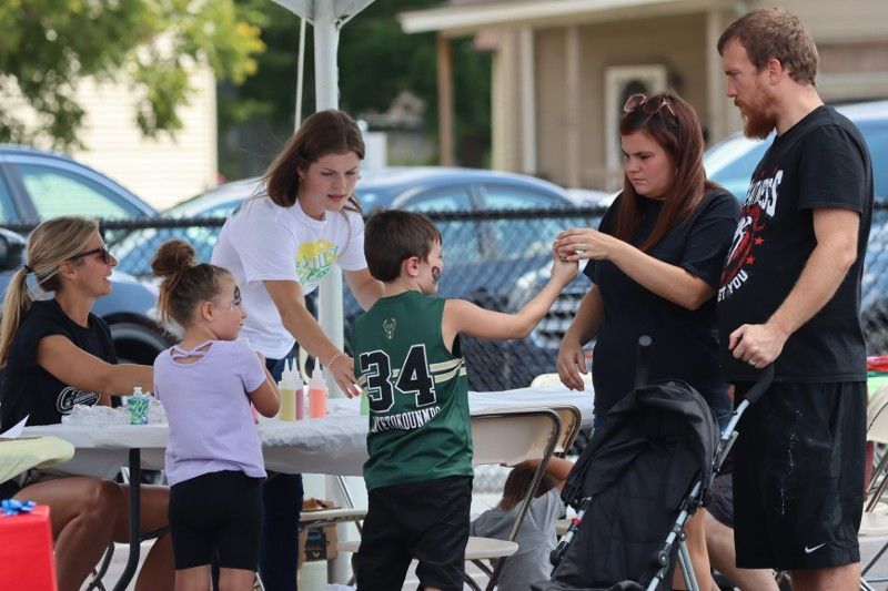 A group of people are standing around a table with a boy wearing a green jersey with the number 34 on it.