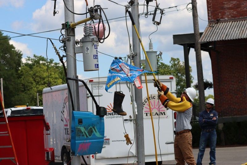 A man is working on a power pole with a flag hanging from it.