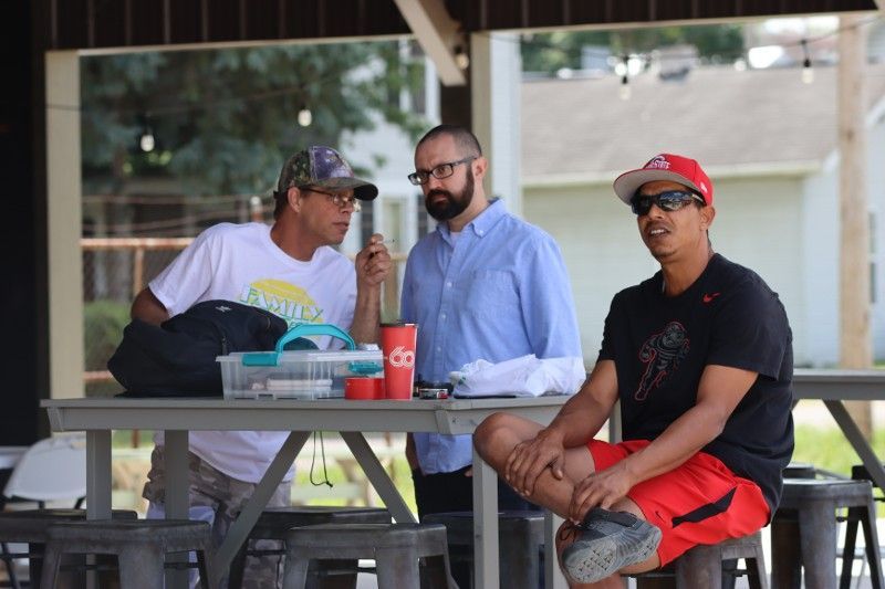Three men are sitting at a picnic table talking to each other