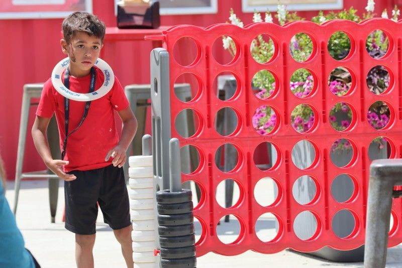 A young boy is standing in front of a giant connect four game.