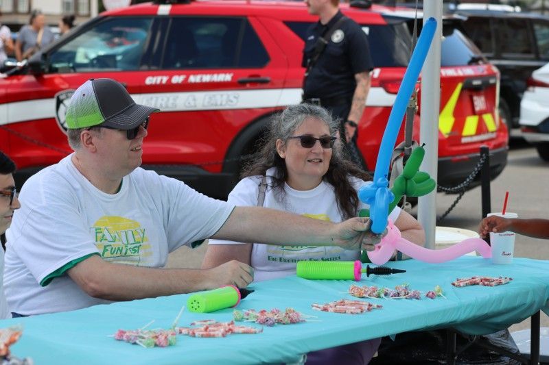 A man and a woman are sitting at a table with balloons on it.