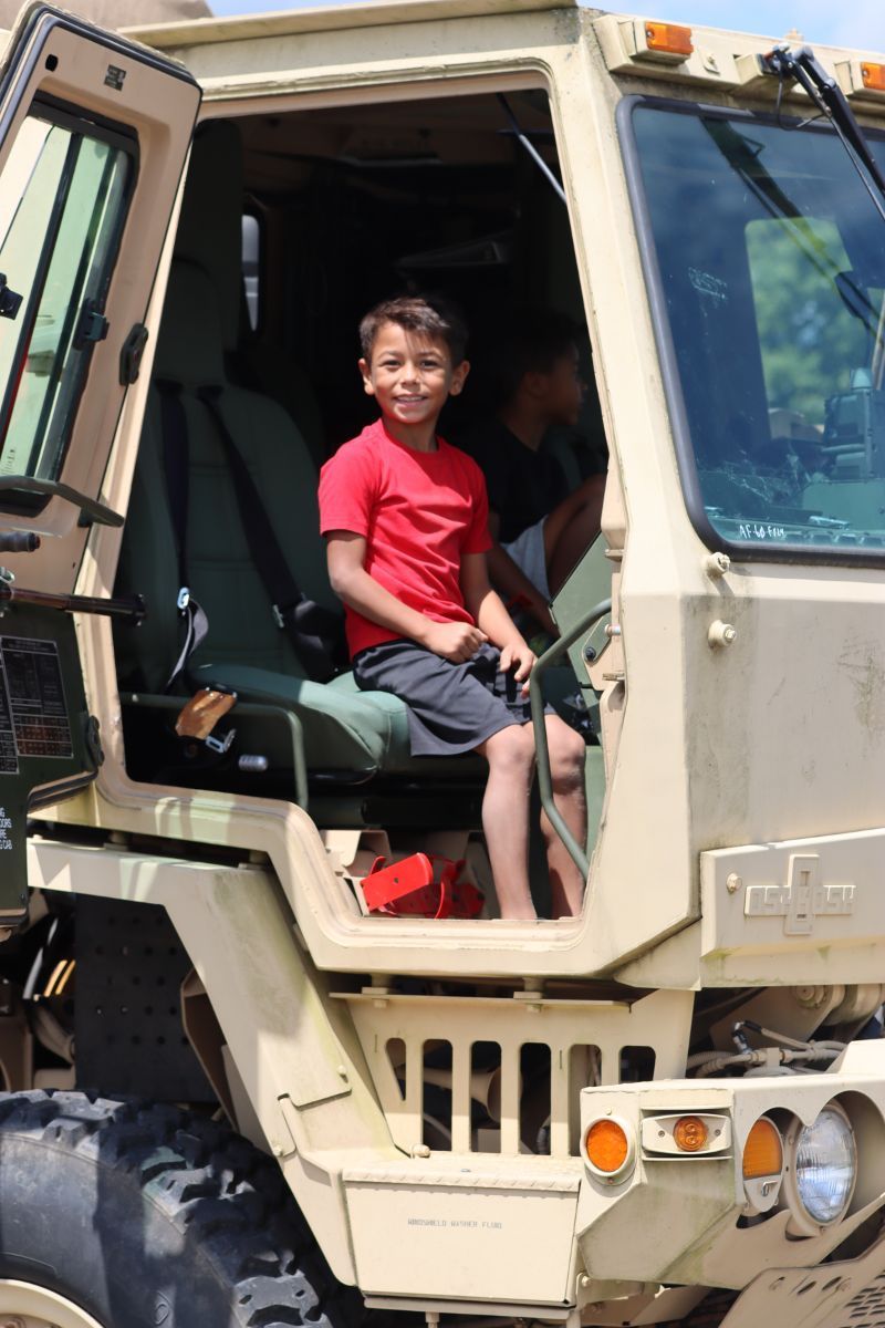 A young boy is sitting in the driver 's seat of a military vehicle.