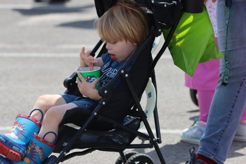 A little boy is sitting in a stroller eating ice cream
