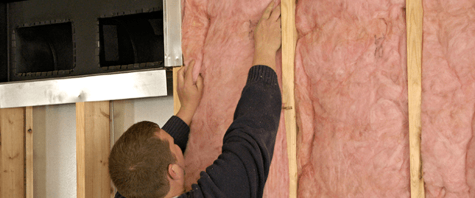 A man putting in fiberglass insulation
