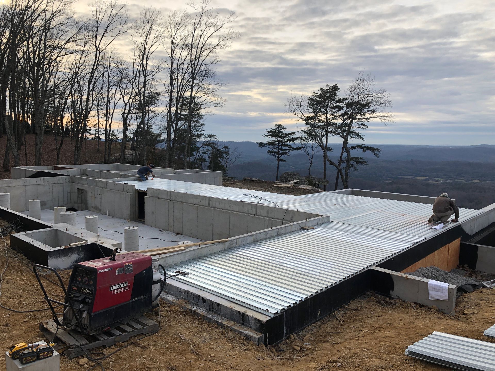 A welding machine is sitting on the ground in front of a house under construction.
