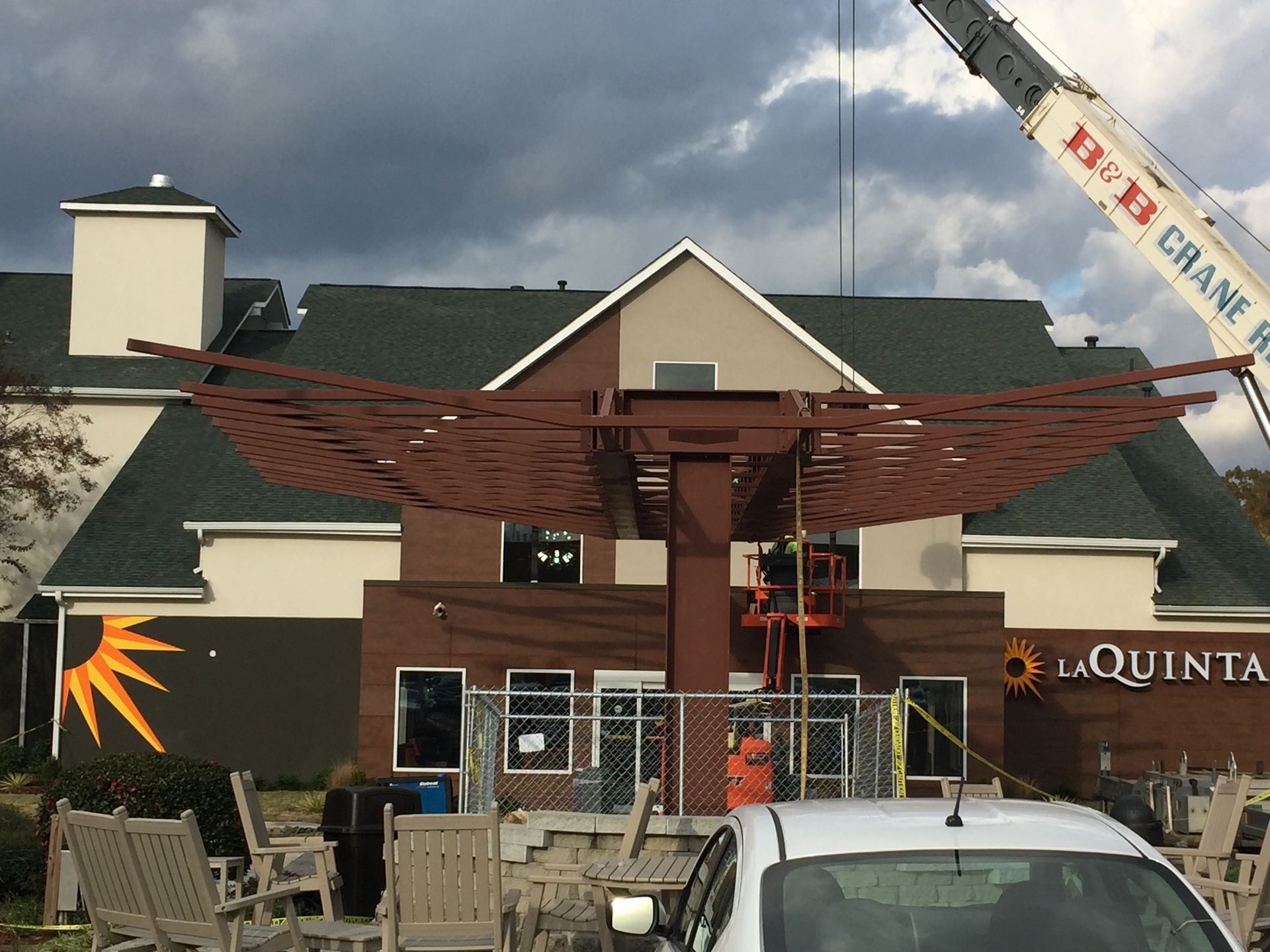 A white car is parked in front of a building that is under construction