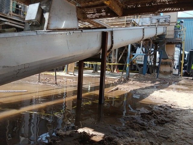 A large pipe is going through a muddy area in a factory
