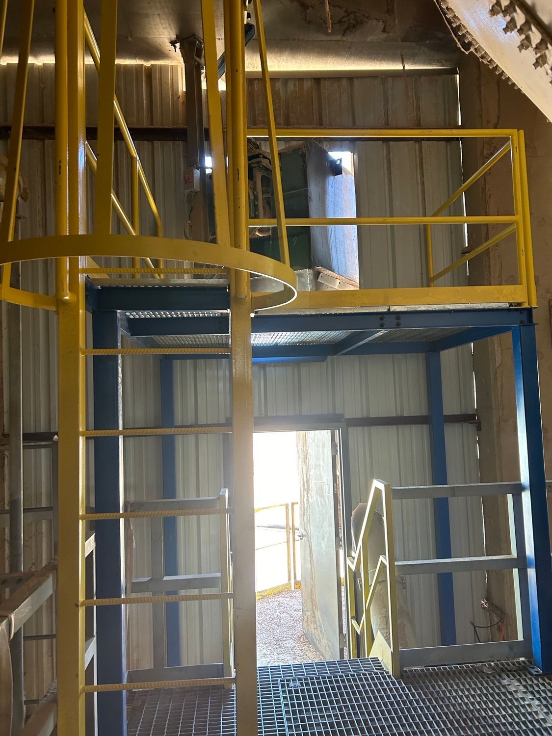 A yellow ladder is leading up to a metal platform in a building