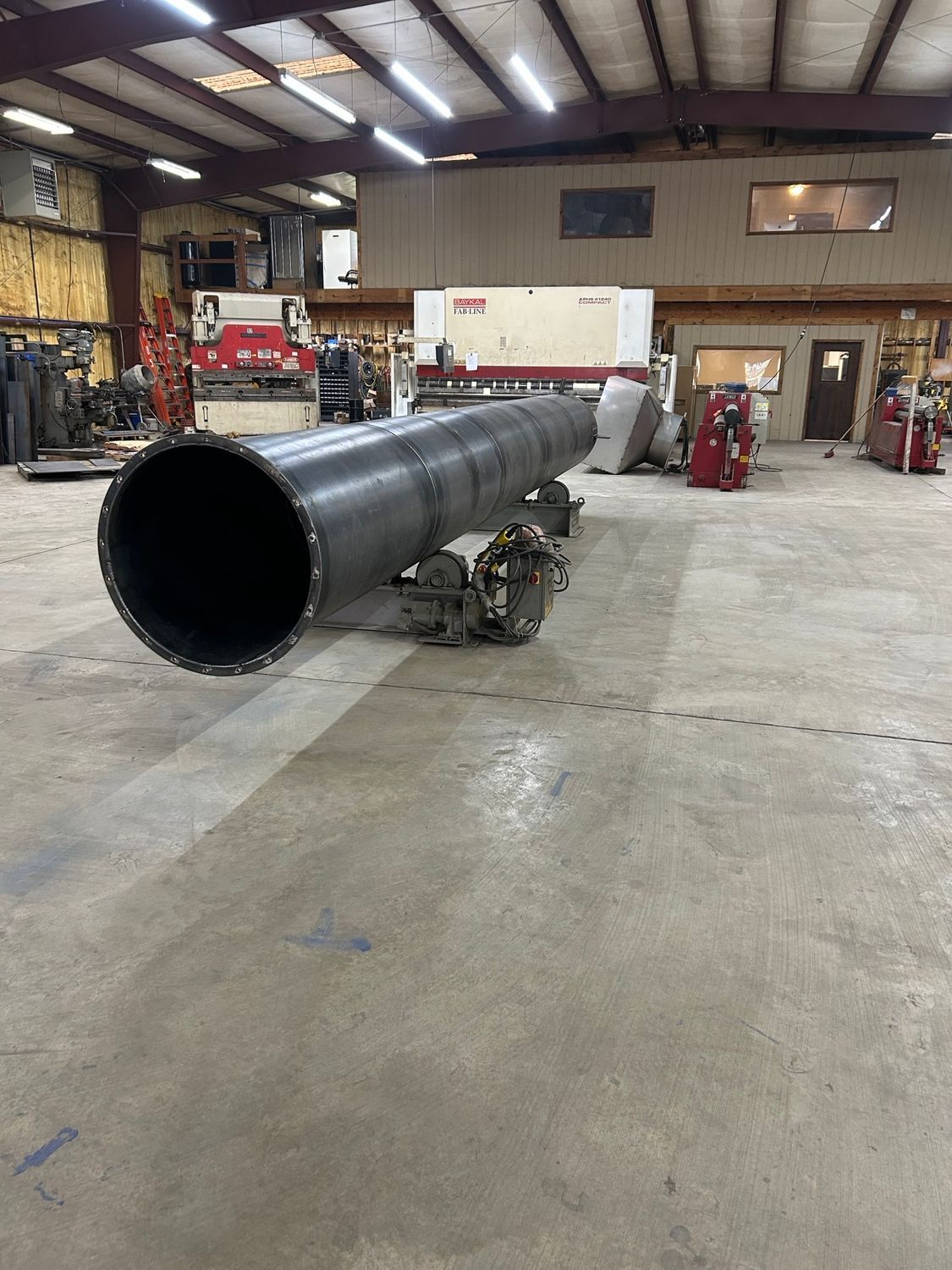 A large metal pipe is sitting on the floor in a factory