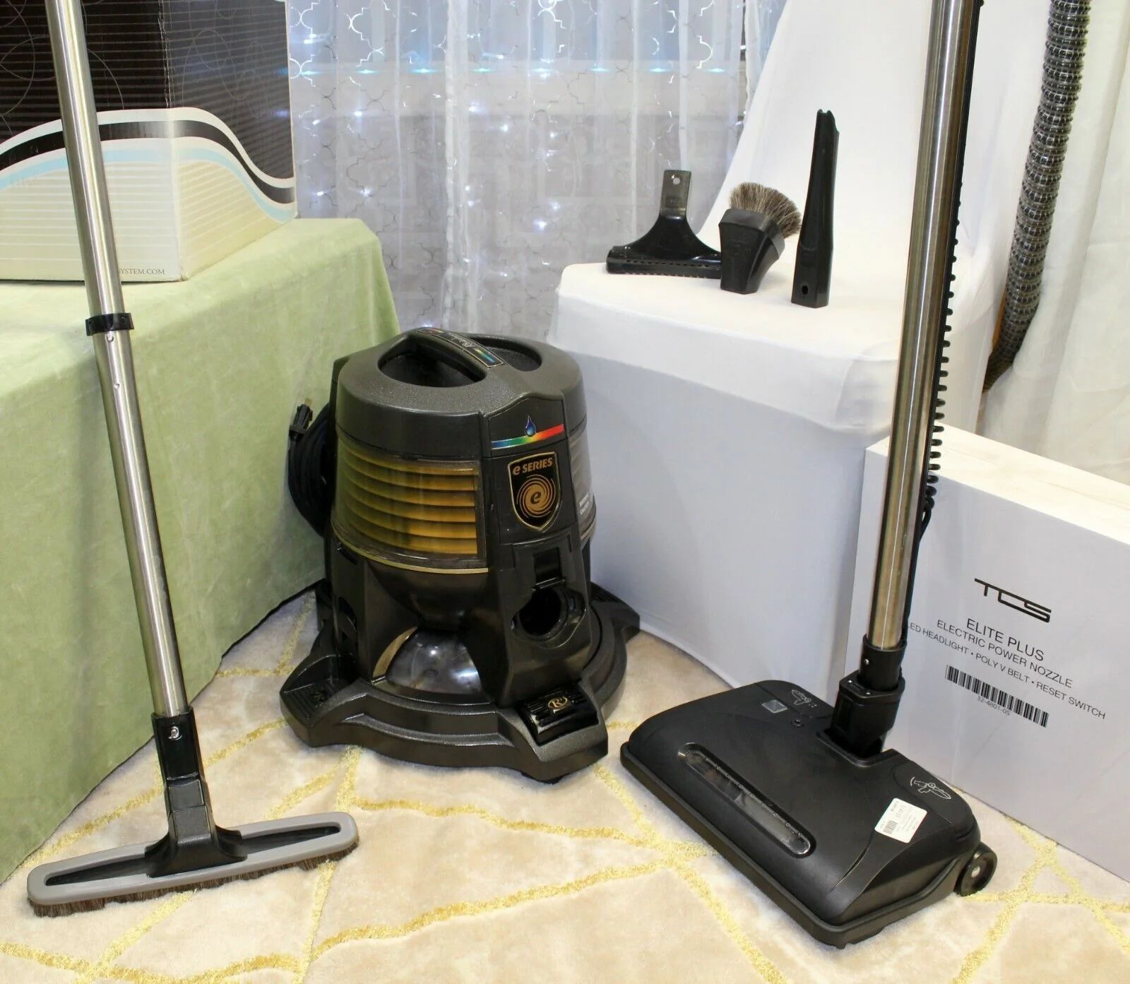 Vacuum cleaners and attachments are displayed in a showroom corner on the floor.