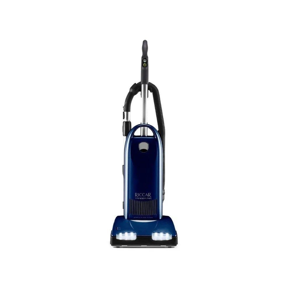 Blue upright vacuum cleaner with a hose and dual front headlights on a white background