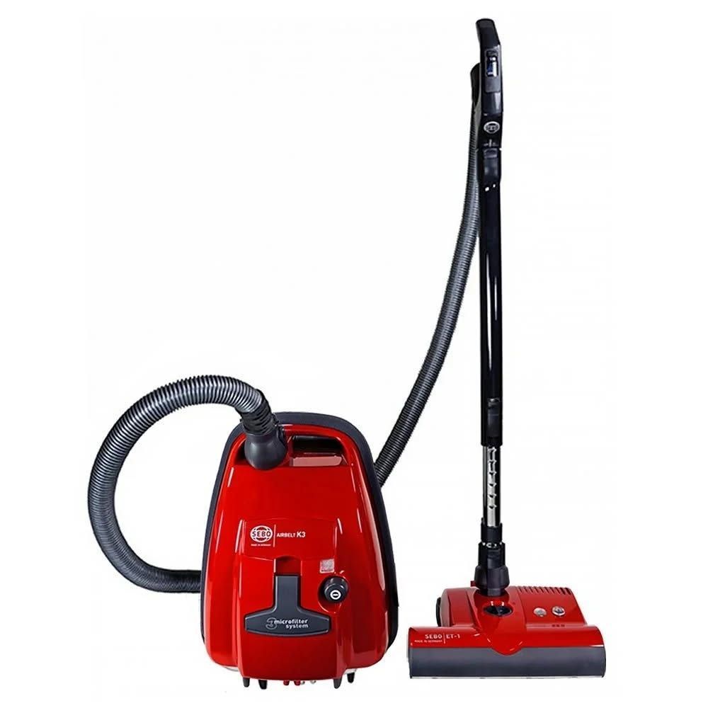 Red canister vacuum cleaner with hose and upright floor nozzle on a white background