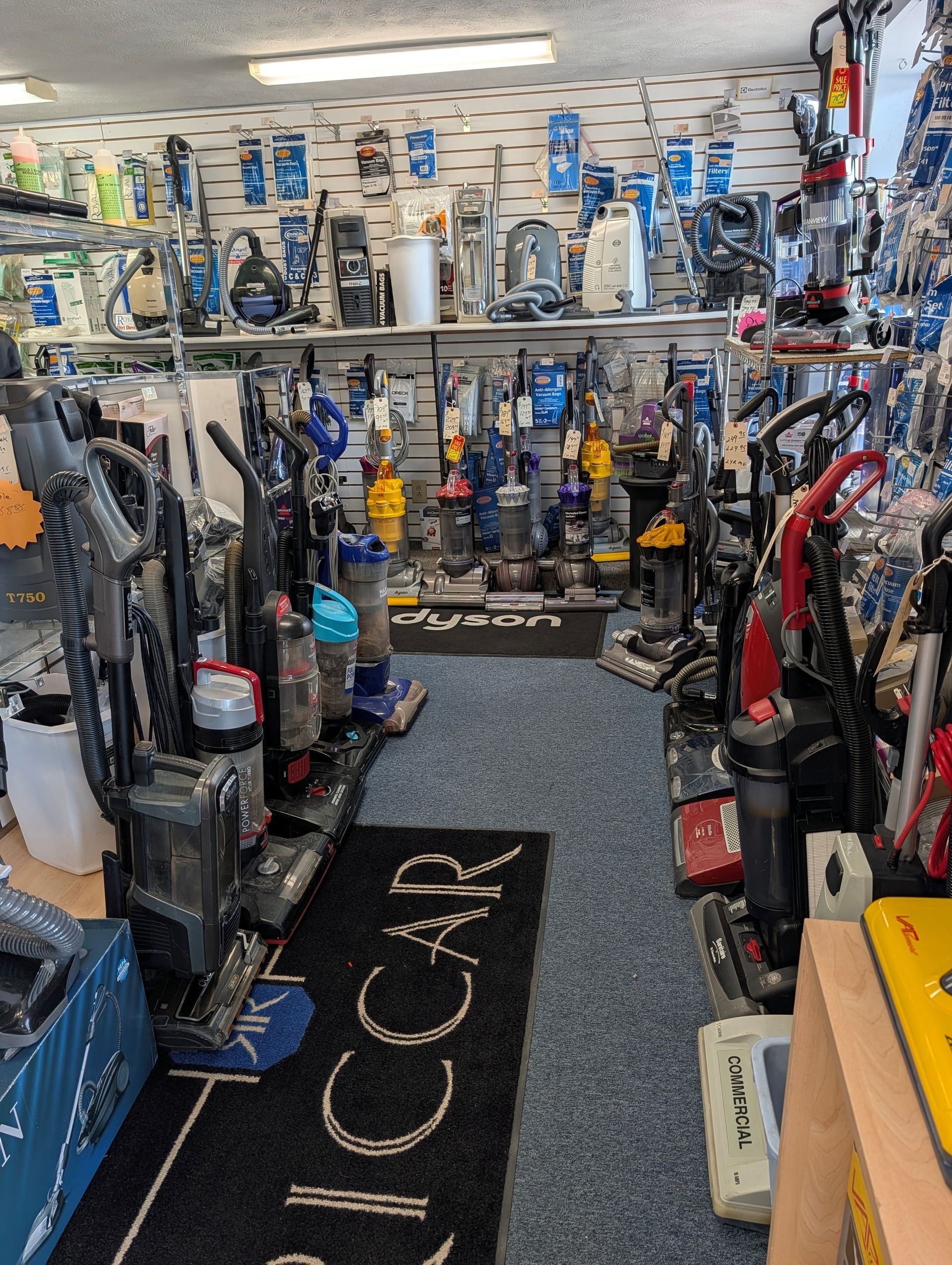 Vacuum cleaner store aisle with rows of upright and canister vacuums on display